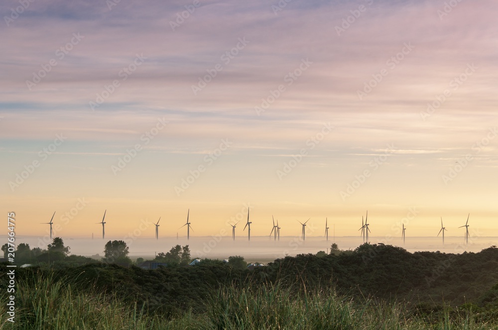 Wind turbines rising out of the mist at sunrise on a summer's morning