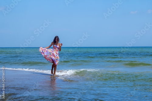 Young beautiful woman dancing in water of sea as symbol of freedom and happiness. Sunlight reflection in water.