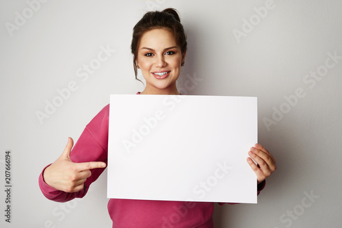 Pretty smiling woman holding empty blank board isolated on the gray background