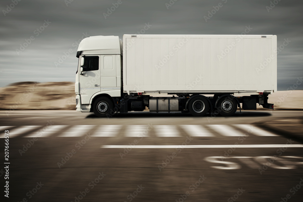 LKW fährt schnell auf einer Straße in der Wüste