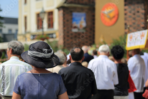 Kobieta w kapeluszu i zgromadzeni ludzie w czasie nabożeństwa Bożego Ciała w Brzegu.