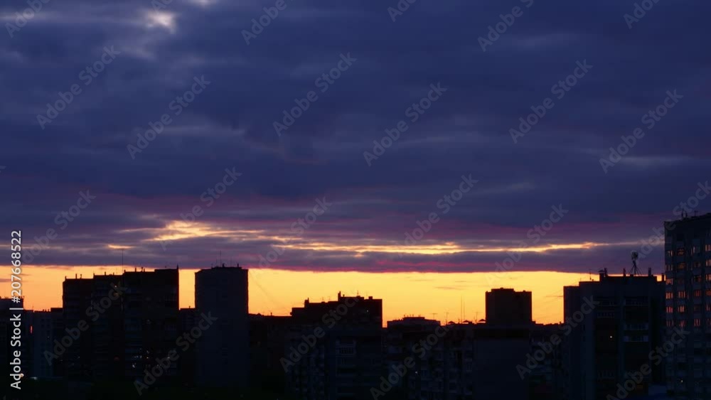 Sunset timelapse at city skyline background. Dark clouds float at golden sky horizon Sunset timelapse at city skyline background. Dark clouds float at golden sky horizon