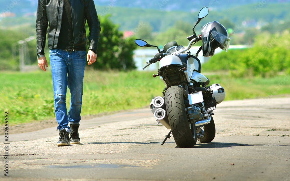 Obraz premium Cool guy in leather jacket and jeans walks to his motorcycle