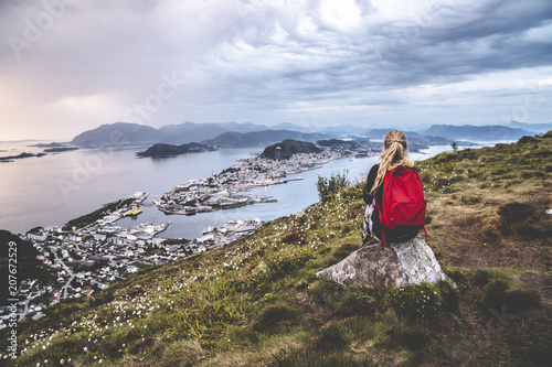 Woman sit on mountaintop looking towards ocean city