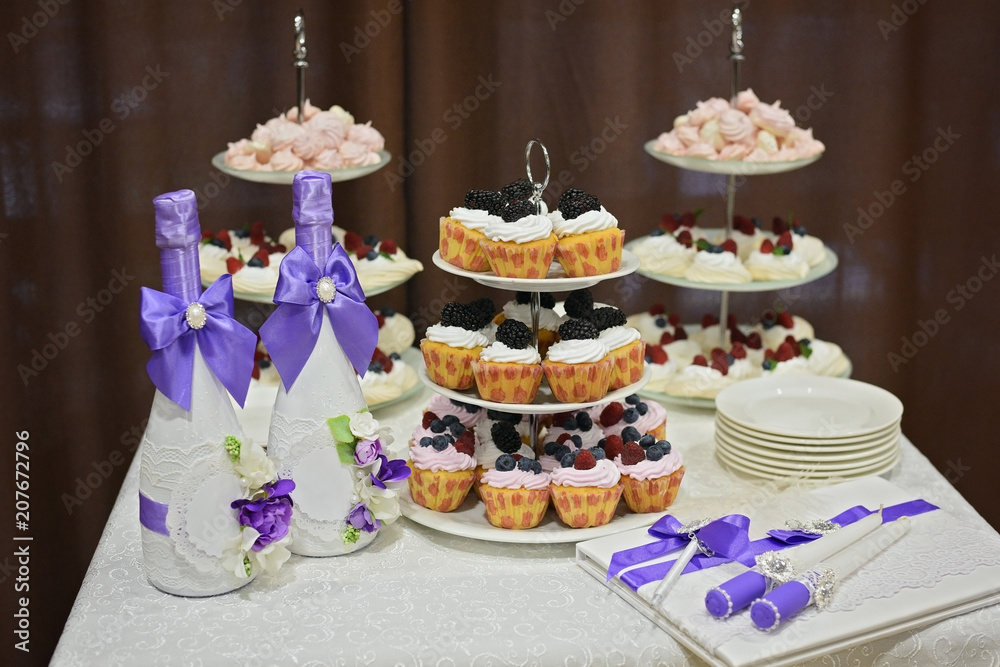 wedding decoration elements, festive table with cupcakes, bottles of champagne with blue ribbons of silk, candles and a guest book