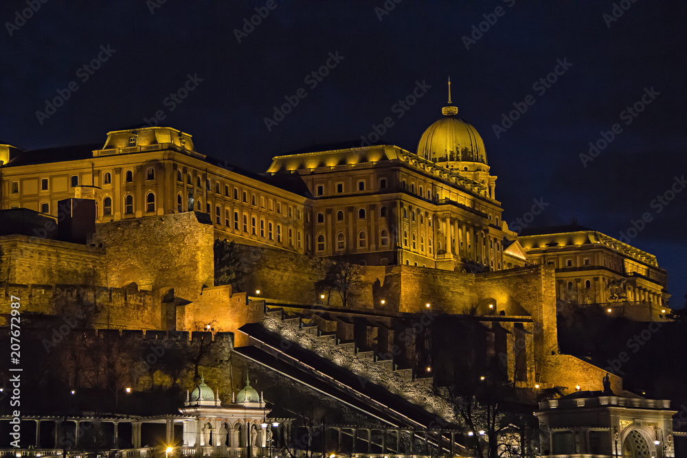 View over Buda side of Budapest with illuminated Buda castle and Danube river from viewpoint on a touristic motor ship at night in Budapest, Hungary
