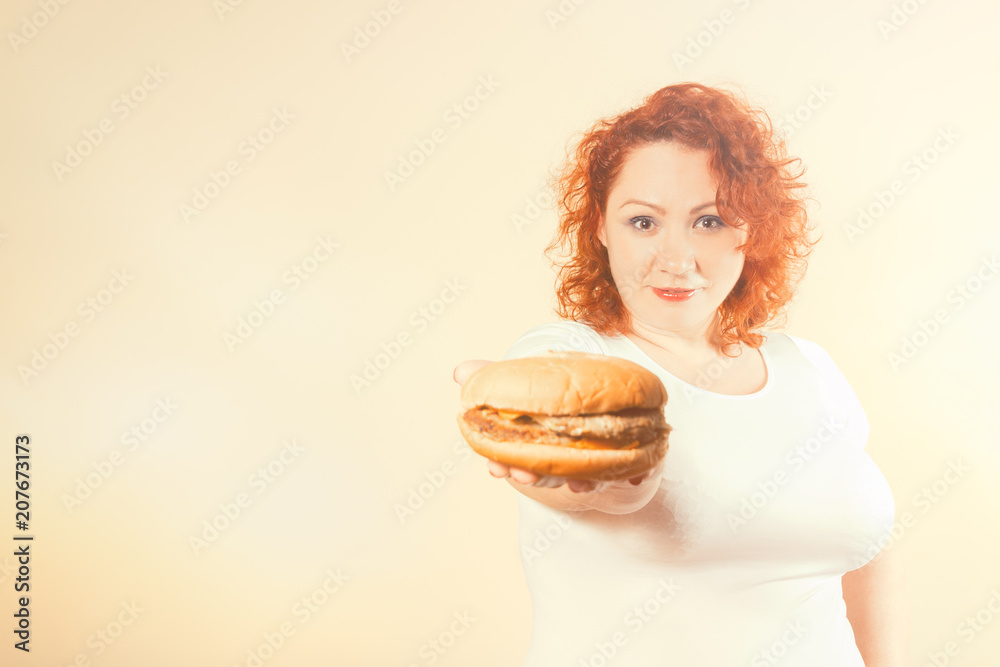 Big woman eat fast food. Red hair fat girl with burger. Unhealthy food concept with plus size female Big woman eat fast food. Red hair fat girl with burger. Unhealthy food concept with plus size female
