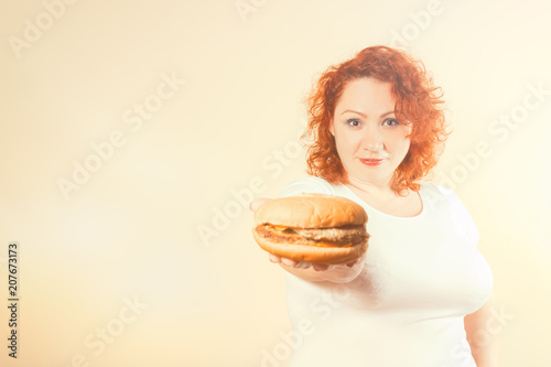 Big woman eat fast food. Red hair fat girl with burger. Unhealthy food concept with plus size female