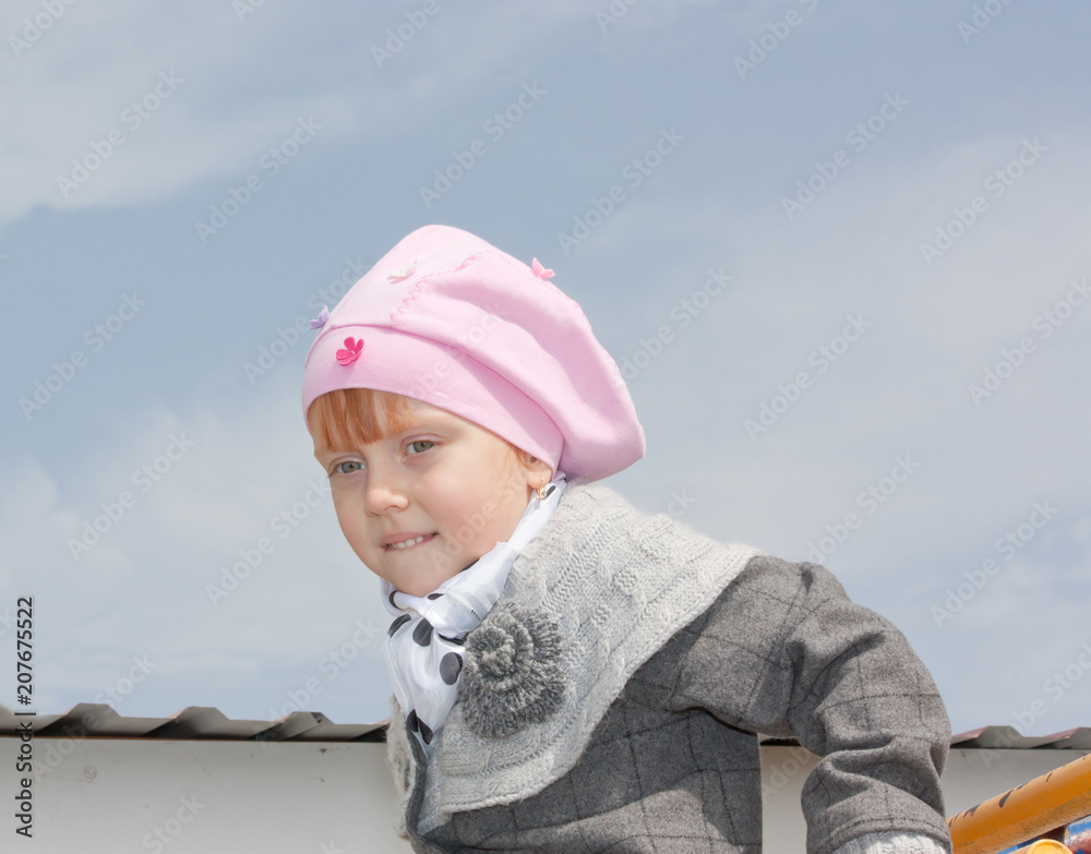 Beautiful little girl playing on gym bars in park
