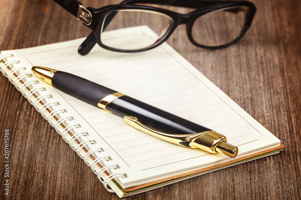 Notepad and pen on a wooden background