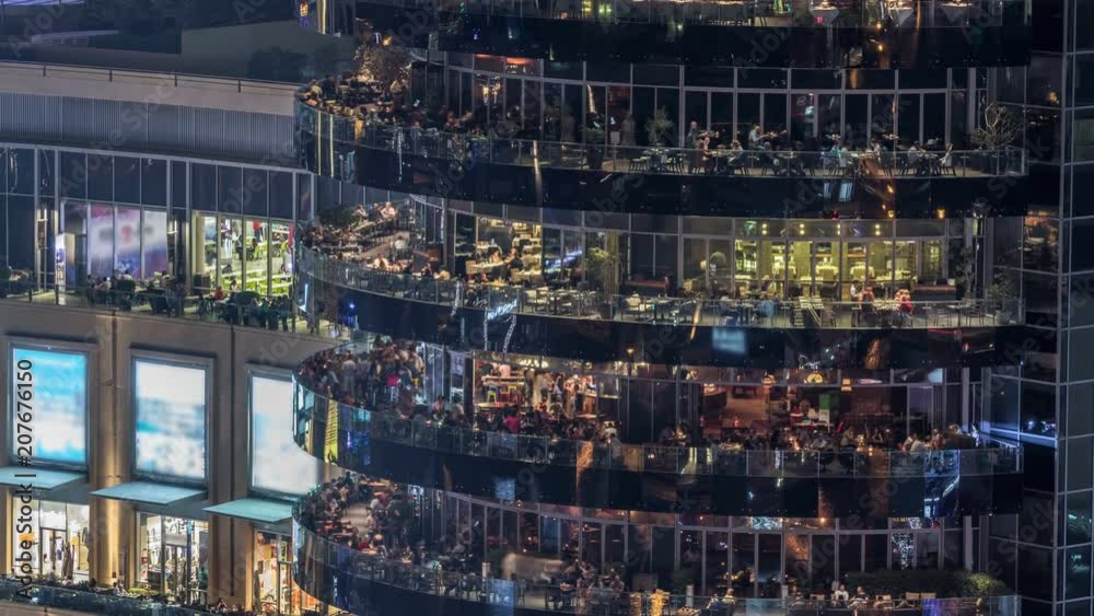 Aerial vew of Dubai Marina promenade with restaurants from skyscraper night timelapse, United Arab Emirates.