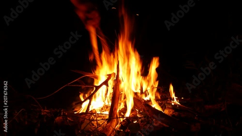 Video footage of a burning and sparking campfire at night with burning woods in 4K resolution.
