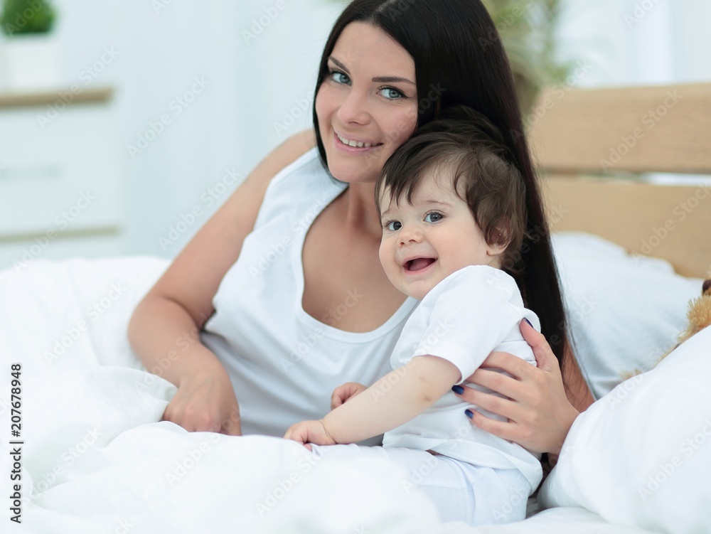 Portrait of a beautiful mother with her baby in the bedroom Portrait of a beautiful mother with her baby in the bedroom