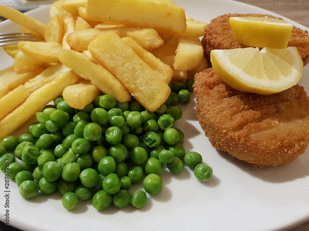 Tasty lunch in English style - fish cakes, chips, peas on a white plate Tasty lunch in English style - fish cakes, chips, peas on a white plate