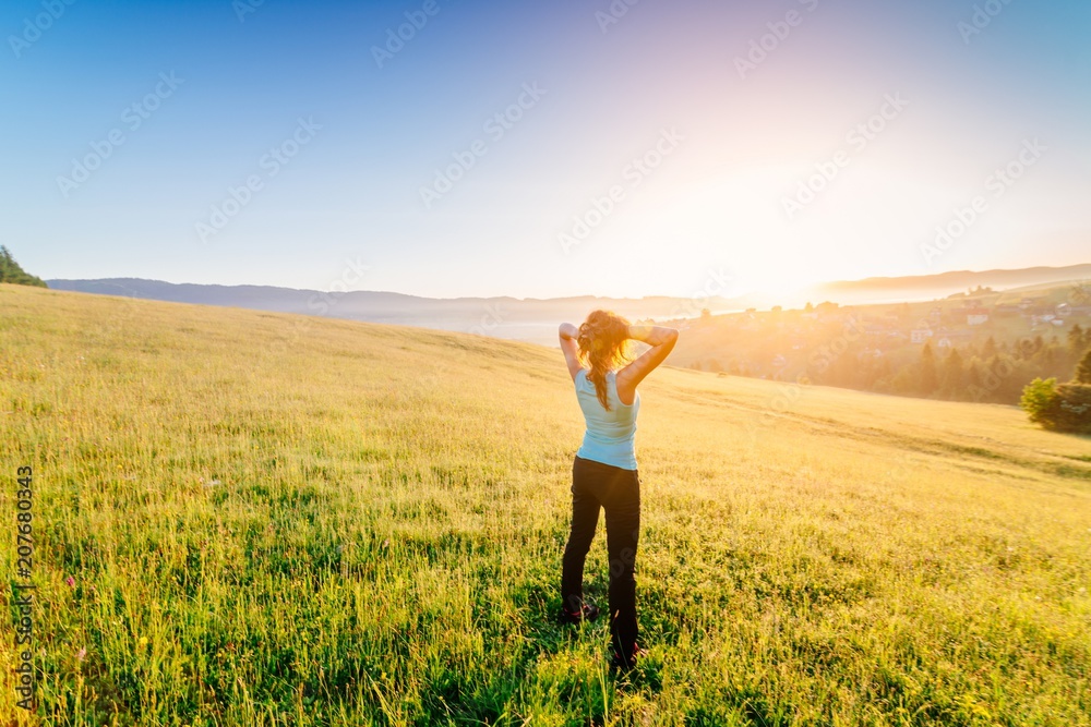 Woman at summer meadow enjoying beauty morning in mountain Woman at summer meadow enjoying beauty morning in mountain