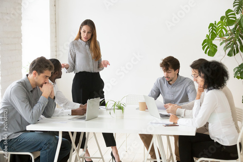 Serious businesswoman scolding employees for bad work results during company meeting, female team leader lecturing workers for poor financial rating at business briefing. Leadership concept