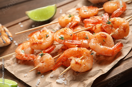 Skewers with delicious fried shrimps on wooden board, closeup