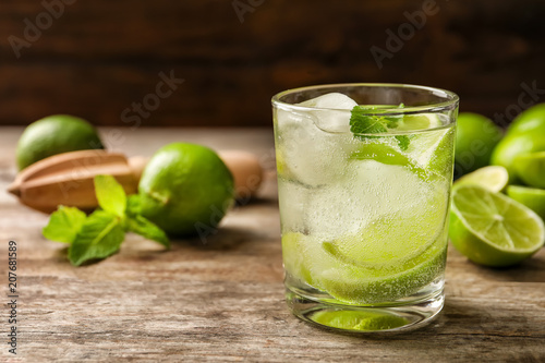 Refreshing beverage with mint and lime in glass on table