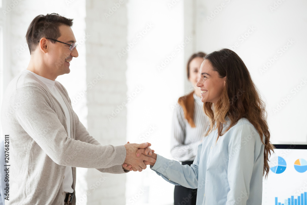 CEO congratulating proud excited shy female intern with job promotion, shaking hand greeting with successful startup project, welcoming new hired business team member. Reward, human resources concept