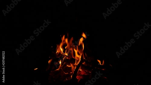 Video footage of a burning and sparking campfire at night with burning woods in 4K resolution.