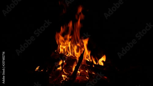 Video footage of a burning and sparking campfire at night with burning woods in 4K resolution.