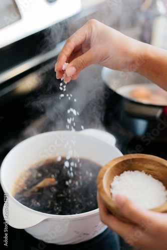 Hand sprinkling salt into boiling pot