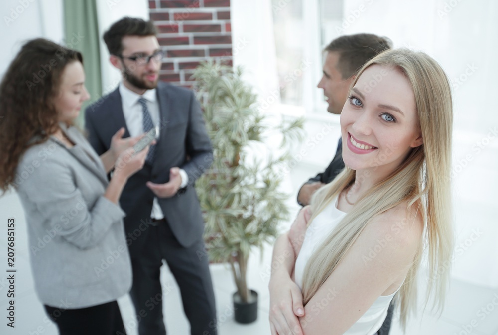 successful young woman - a company employee against the backdrop of colleagues successful young woman - a company employee against the backdrop of colleagues