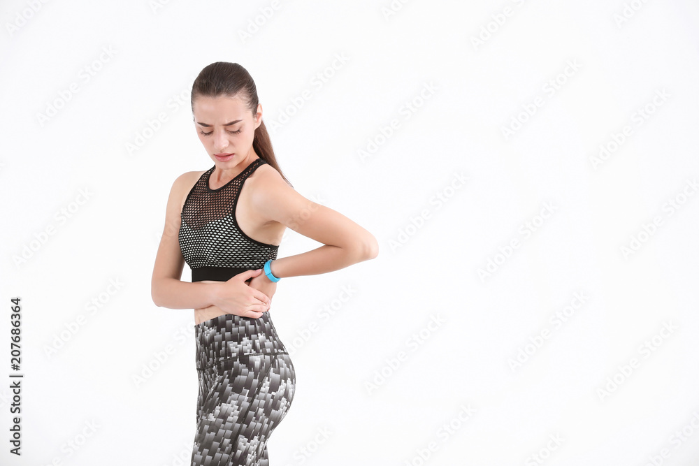 Woman in sportswear suffering from flank pain on white background Woman in sportswear suffering from flank pain on white background