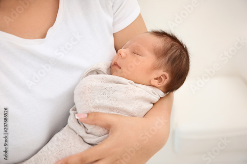 Young mother holding cute newborn baby, closeup