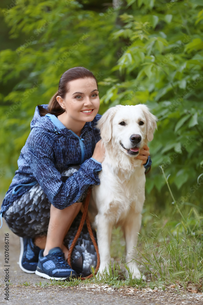 Young woman with her dog together in park. Pet care