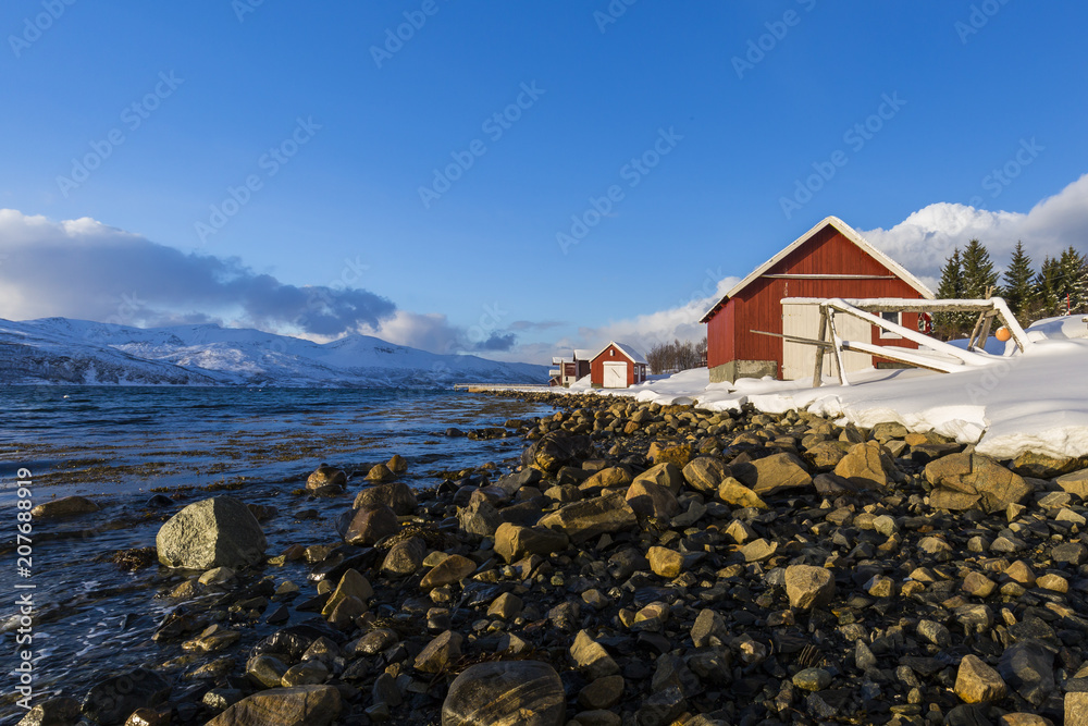 Typical norwegian warm and cosy house located at the lakeside at a fjord in a snowy winter landscape. Typical norwegian warm and cosy house located at the lakeside at a fjord in a snowy winter landscape.