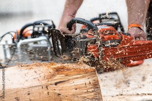 chainsaw in action with flying sawdust and motion blur, man is cutting a tree trunk with his power saw