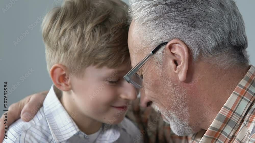 Smiling aged man hugging grandson with love, generations connection, closeness