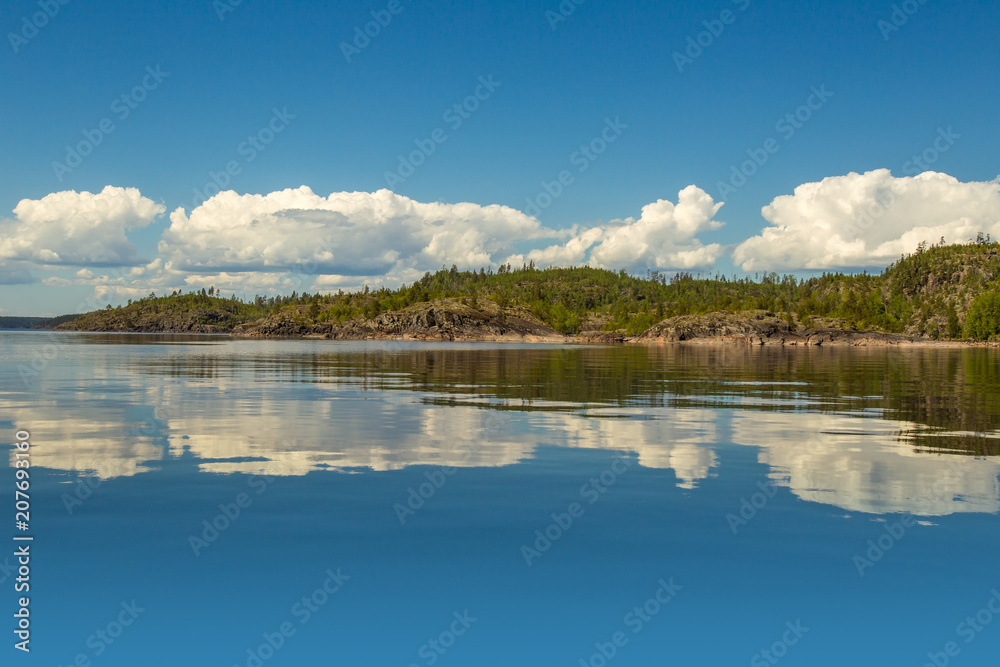 Karelia. Russia. Nature of Karelia. Northern nature of Russia. Reflection of the island in the water. Reflection of the clouds input. Summer day.