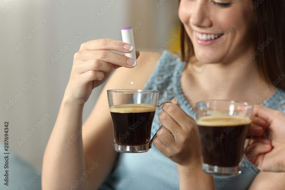 Woman hand throwing saccharine into a coffee cup Woman hand throwing saccharine into a coffee cup