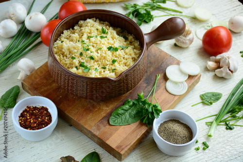 Bulgur in plate on wooden table. Traditional middle eastern or arab dish. Top view. vegetarian dinner. Bulgur  with vegetables, spices on white background. Flat la photo