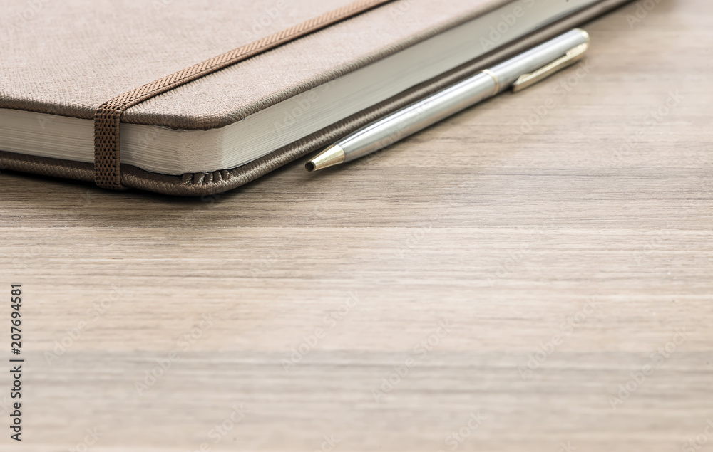 Pen and notebook up close on a wooden desk Pen and notebook up close on a wooden desk