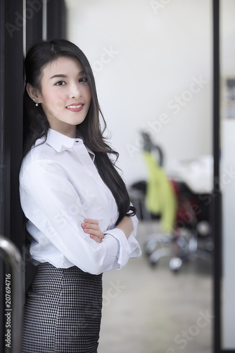 businesswoman smiling and standign at the door of her office and looking at camera