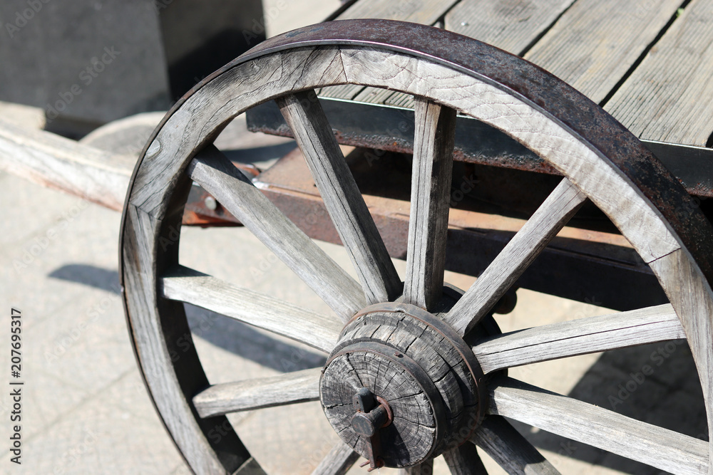 A partial image of a wagon with wooden wheels. 