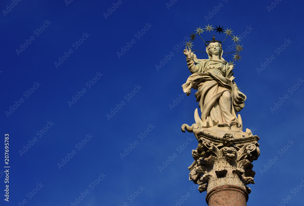 Statue of Virgin Mary of the Stars crushing dragon and crescent at the top of an ancient column in the historic center of Lucca, erected in 1687 (with copy space)