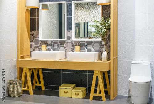 White tile bathroom interior with a concrete floor, a double sink standing on a wooden shelf and a shower.