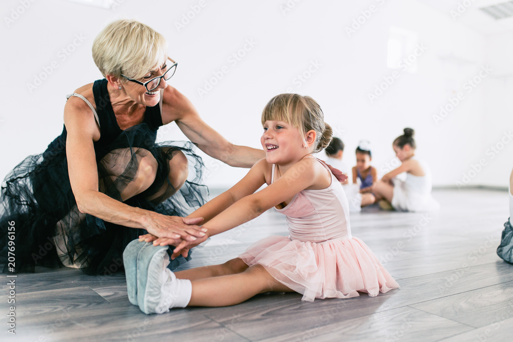 Naklejka premium Charming senior ballet teacher learning little ballerina how to dance.