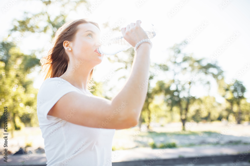 Young sports girl, drinking water from the bottle, after a hard workout, can be used for advertising, text insertion Young sports girl, drinking water from the bottle, after a hard workout, can be used for advertising, text insertion