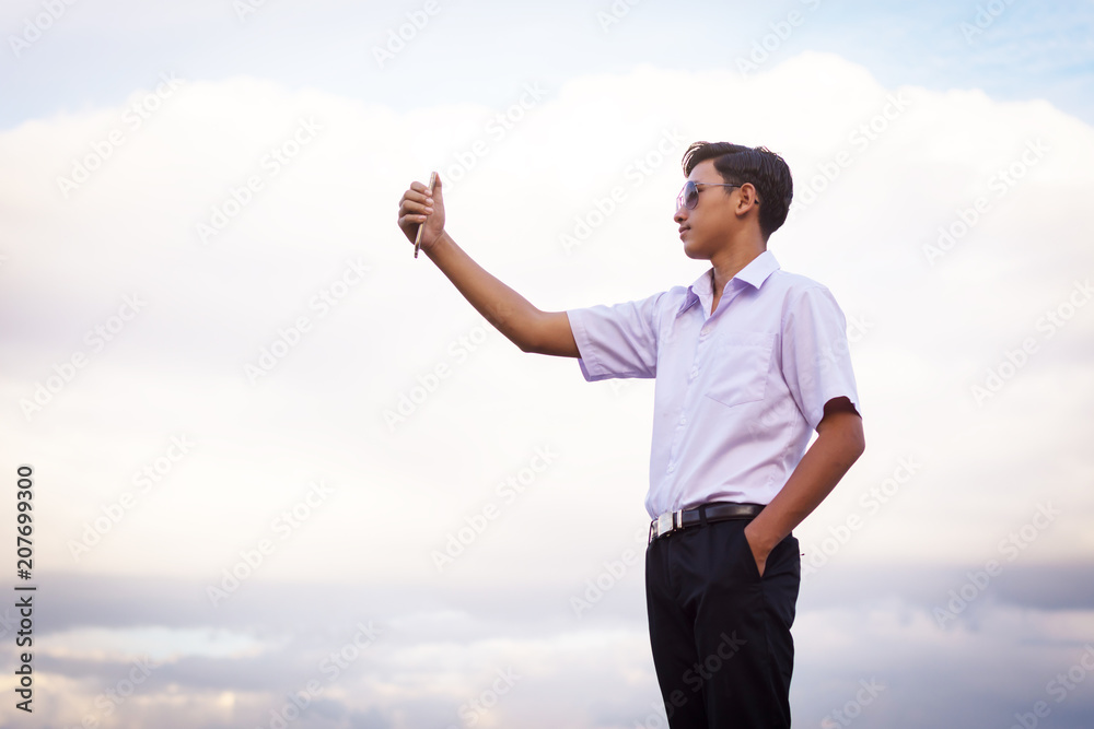 Young man photographing himself with a mobile phone camera standing on the waterfront. Young man photographing himself with a mobile phone camera standing on the waterfront.