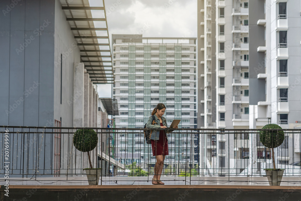 Asian Businesswoman with casual suit standing and working with laptop around outdoor of modern Office or workplace in city