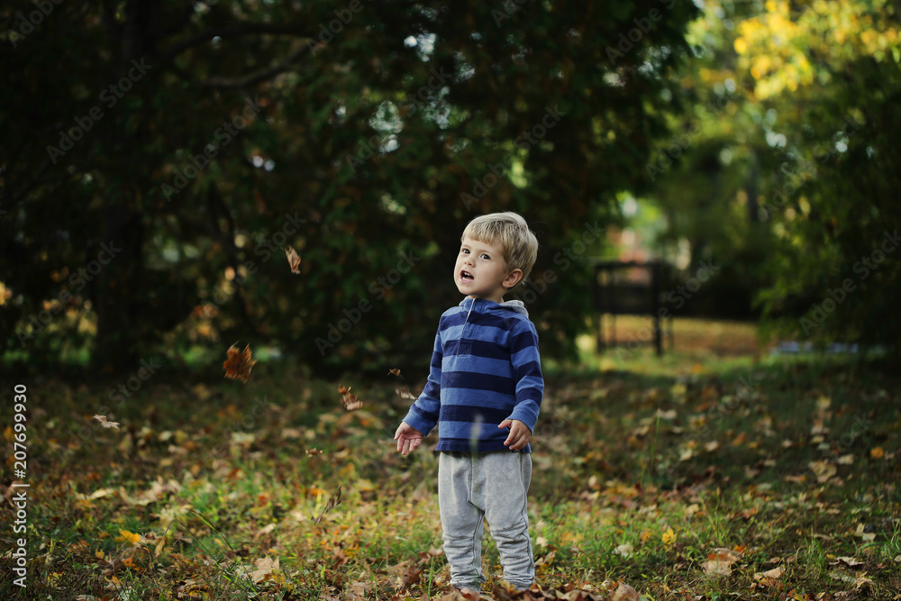 Little boy, playing in the rain in autumn park, leaves around him Little boy, playing in the rain in autumn park, leaves around him