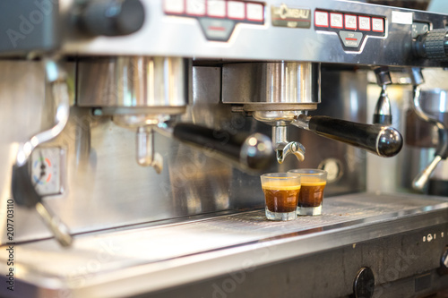 Black coffee being prepared from coffee machine into glass cup. Professional coffee brewing, hot coffee.