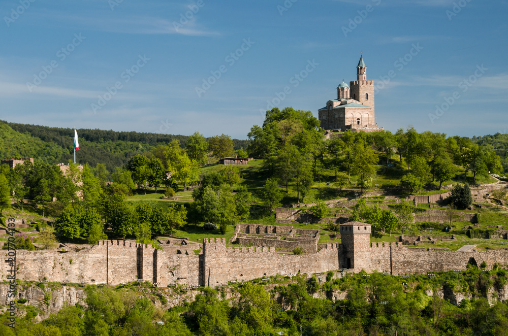 Scenic view on Veliko Tarnovo, Bulgaria. Famous landmarks of the city: castle on  Tsarevets hill,  medieval churches, ancient stone bridge. Traditional bulgarian architecture. Sunny spring day.