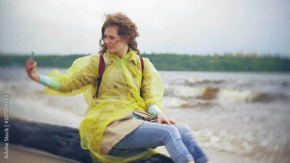 Happy woman walking along the coast Traveling Lifestyle adventure vacation outdoors. A girl dressed in a fashionable yellow raincoat Happy woman walking along the coast Traveling Lifestyle adventure vacation outdoors. A girl dressed in a fashionable yellow raincoat