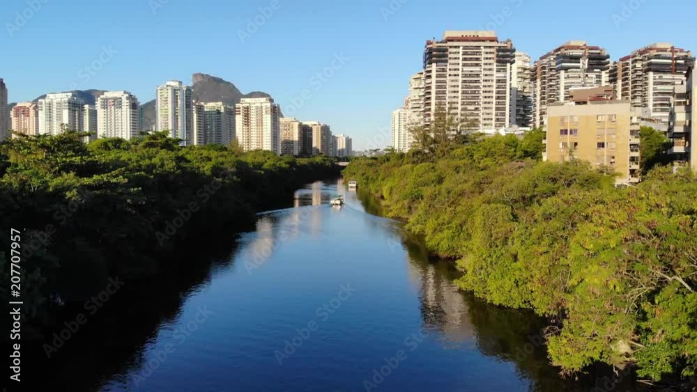 Drone aerial Hyperlapse of Marapendi canal in Barra da Tijuca on a summer day, with a boat slowly traveling along river. Tall residential skyscrapers on both sides, with green vegetation Drone aerial Hyperlapse of Marapendi canal in Barra da Tijuca on a summer day, with a boat slowly traveling along river. Tall residential skyscrapers on both sides, with green vegetation